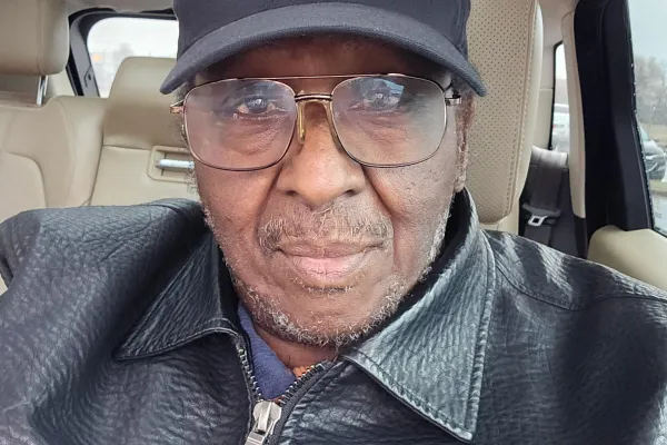 photo of Wayne Bostick in his car wearing glasses, a hat, and a leather jacket with a NC voter sticker on it